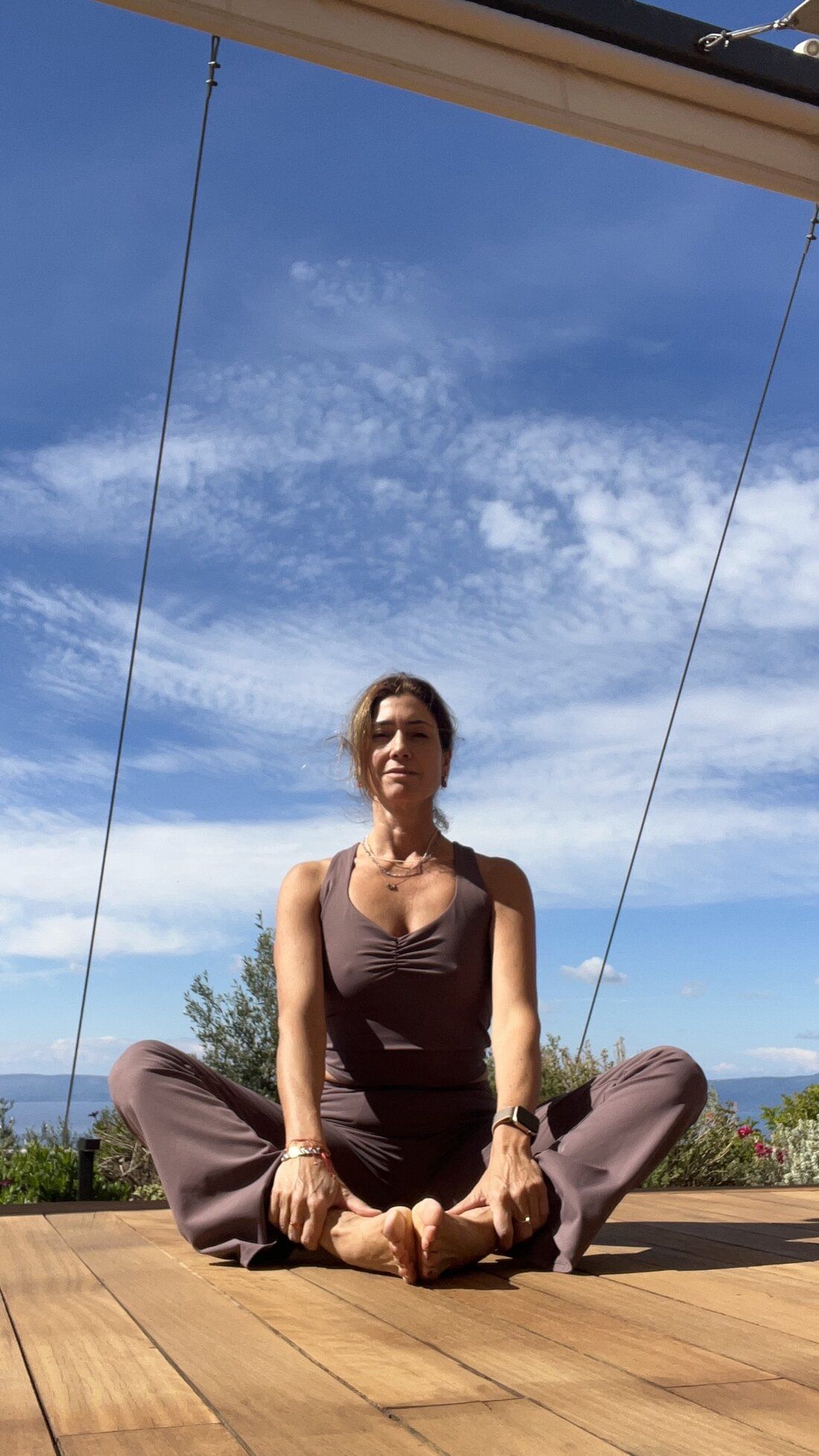 Burcin seated in bound angle pose on a sunny terrace