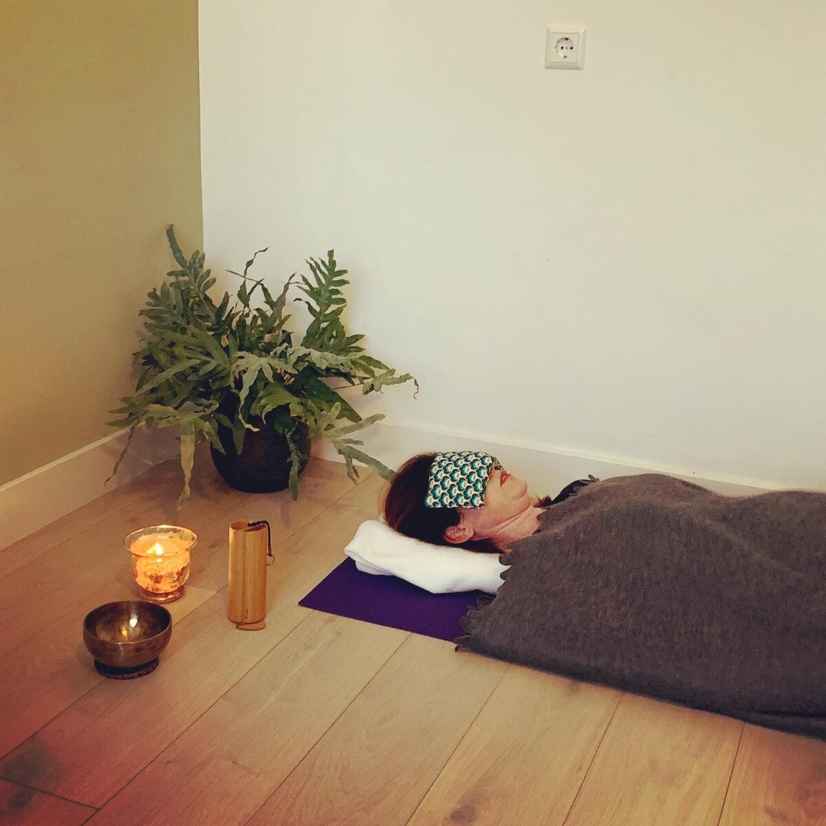 Resting in savasana with an eye pillow and blanket